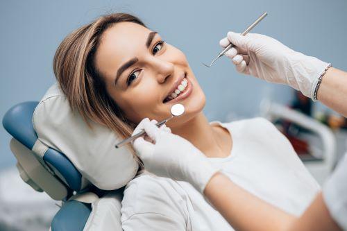Woman in dental chair smiling after oral cancer screening, wilmington de